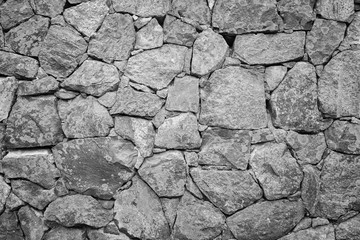 Old surrounding wall at a fortress made of stones with lichen in black and white.