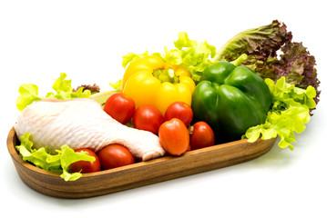 Raw chicken and vegetables in wooden tray