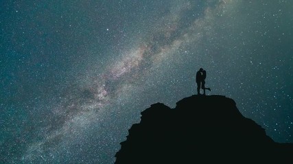 The couple kissing on a mountain on a starry sky background. night time - Powered by Adobe
