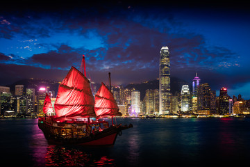 Victoria Harbour Hong Kong night view with junk ship on foreground - obrazy, fototapety, plakaty