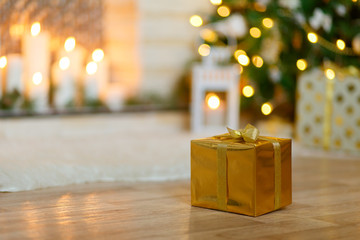 Christmas gift amid Christmas trees, gifts, fireplace, candles, garlands, lights. Postcard