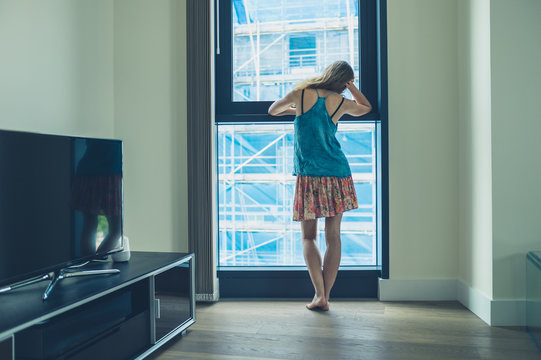 Young woman looking out window of apartment