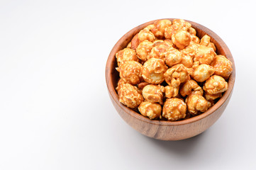 Caramel popcorn in a wooden bowl isolated on white background