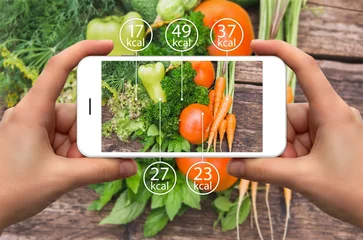 Foto op Plexiglas Smartphone in hand with information of calories in vegetables. © scharfsinn86