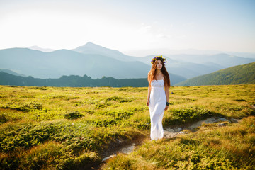 Beauty woman portrait with wreath from flowers on head, Beautiful young long hair woman posing in high mountain scenery. Rocky mountain