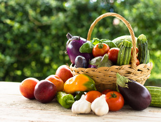 Fresh summer vegetables, collected in a basket of wicker, on a old wooden background.