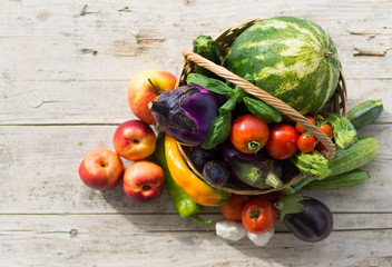 Fresh summer vegetables, collected in a basket of wicker, on a old wooden background.