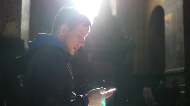 A man stands in a dark room with a telephone, a ray of light falls from the window and is reflected. slow motion. 1920x1080. full hd