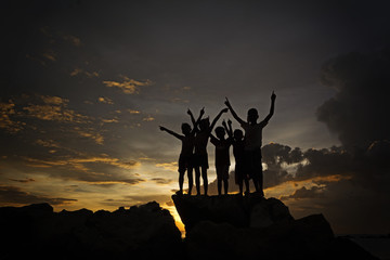A silhouette of joyful kids by the beach