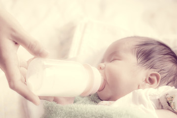 Asian newborn baby drinking milk from bottle