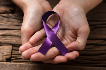 Human Hand Showing Violet Ribbon To Support Breast Cancer Cause