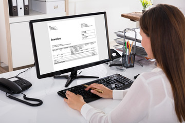 Fototapeta na wymiar Businesswoman Looking At Invoice On Computer