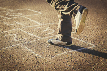 little boy playing hopscotch on playground