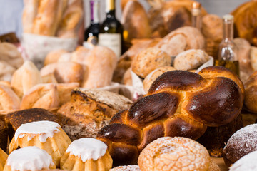 various types of fresh bread in a table: rum baba, challah, wheat and rye breads
