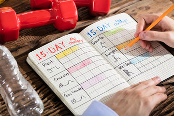 Person Making Exercise Plan On Notebook