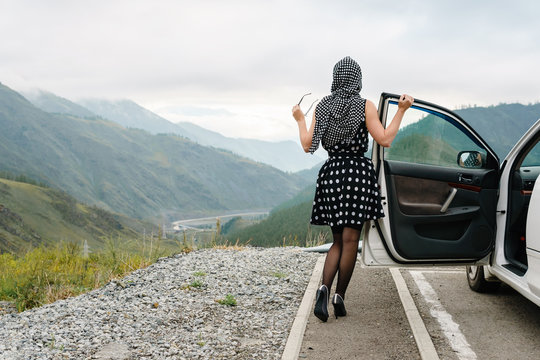 Pin up pose of a young woman on a background of mountains.