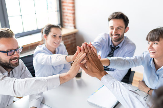 Happy business team giving high five in office.