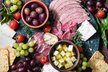 Cheese and meat appetizer selection. Variety of cheese, salami, prosciutto, bread, baguette, grapes, olives