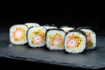 Traditional Japanese cuisine. Selective focus on set of sushi rolls with nori, shrimp, rice and other ingredients on dark background