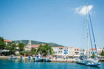 Fototapeta na wymiar Boats big and small parked in the harbor, overlooking the city of Skiathos, Greece