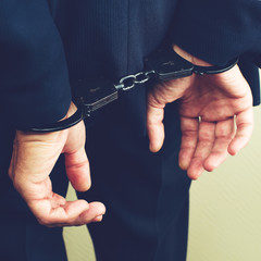 arrested businessman in handcuffs. Businessman bribetaker or briber, toned image. Concept of fraud, detention, crime and bribery