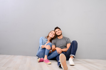 happy young lovely couple sitting on the floor of new home flat apartment with empty space