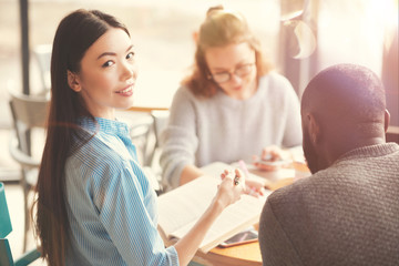 Pleasant young woman studying with her groupmates
