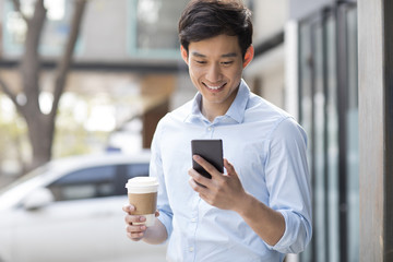 Young businessman with smart phone and coffee