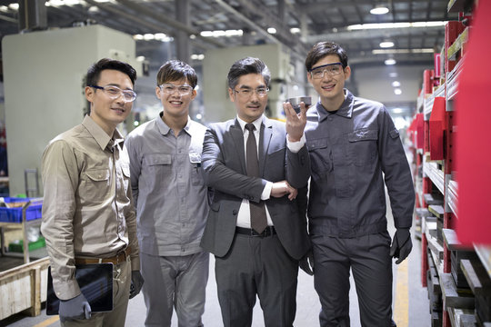 Portrait of businessman and engineers checking machine parts factory