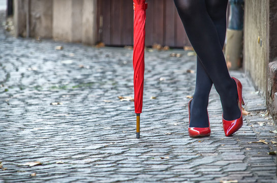 Assembled red umbrella and female feet in red patent leather shoes close-up