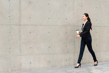 confident business lady walking on gray wall