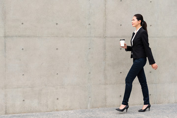 elegant manager woman walking on gray wall