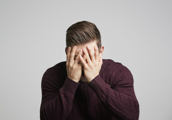 Portrait of a young white man with hands covering his face