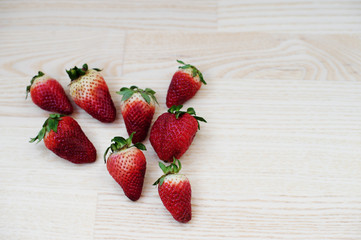 Eight strawberries laying on the table in the shape of heart.