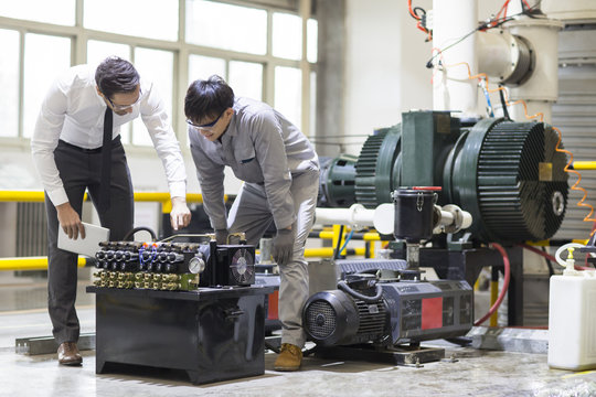 Businessman and engineer checking machine in the factory