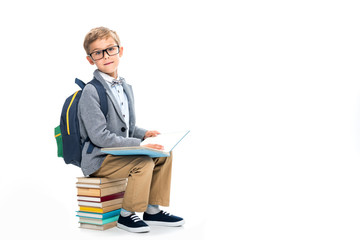 schoolboy sittting on stack of books and reading
