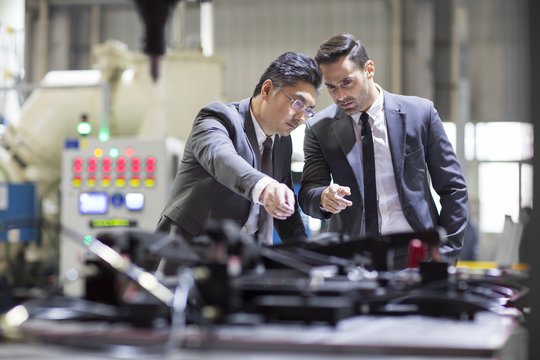 Businessman and engineer checking machine in the factory