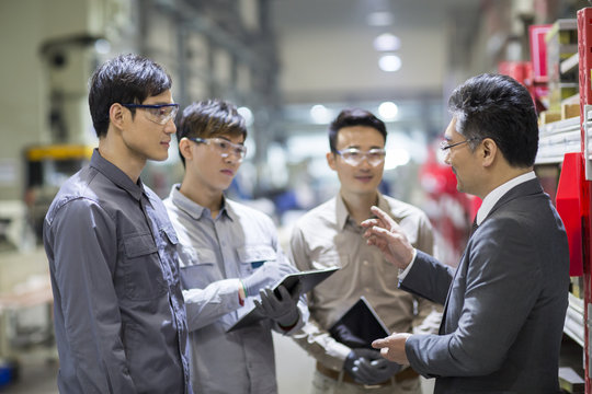 Businessman and engineers talking in the factory