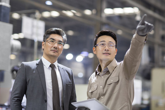 Businessman and engineer talking in the factory