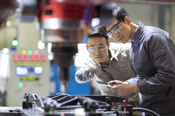 Young engineers checking machine in the factory
