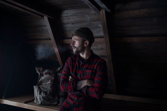 Young man sitting in wooden cabin