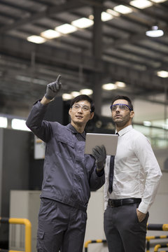 Businessman and engineer talking in the factory