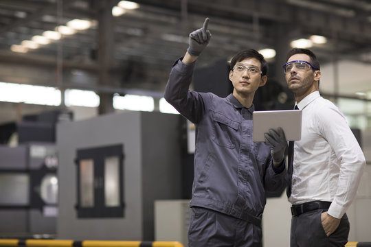 Businessman and engineer talking in the factory
