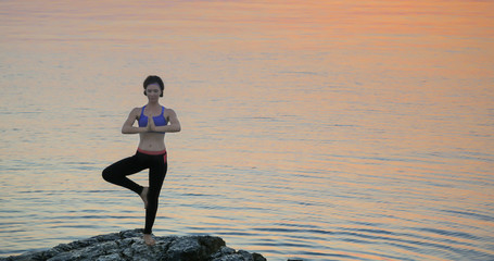 Girl practices yoga near the ocean