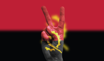 angola national flag painted onto a male hand showing a victory, peace, strength sign - obrazy, fototapety, plakaty
