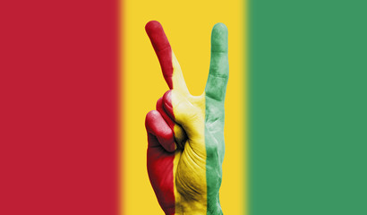 Guinea national flag painted onto a male hand showing a victory, peace, strength sign