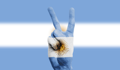 argentina national flag painted onto a male hand showing a victory, peace, strength sign