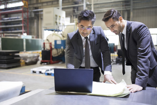 Businessman and engineer talking in the factory