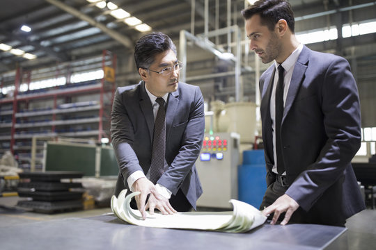 Businessman and engineer talking in the factory