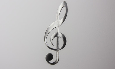 Metal treble clef on a white wall